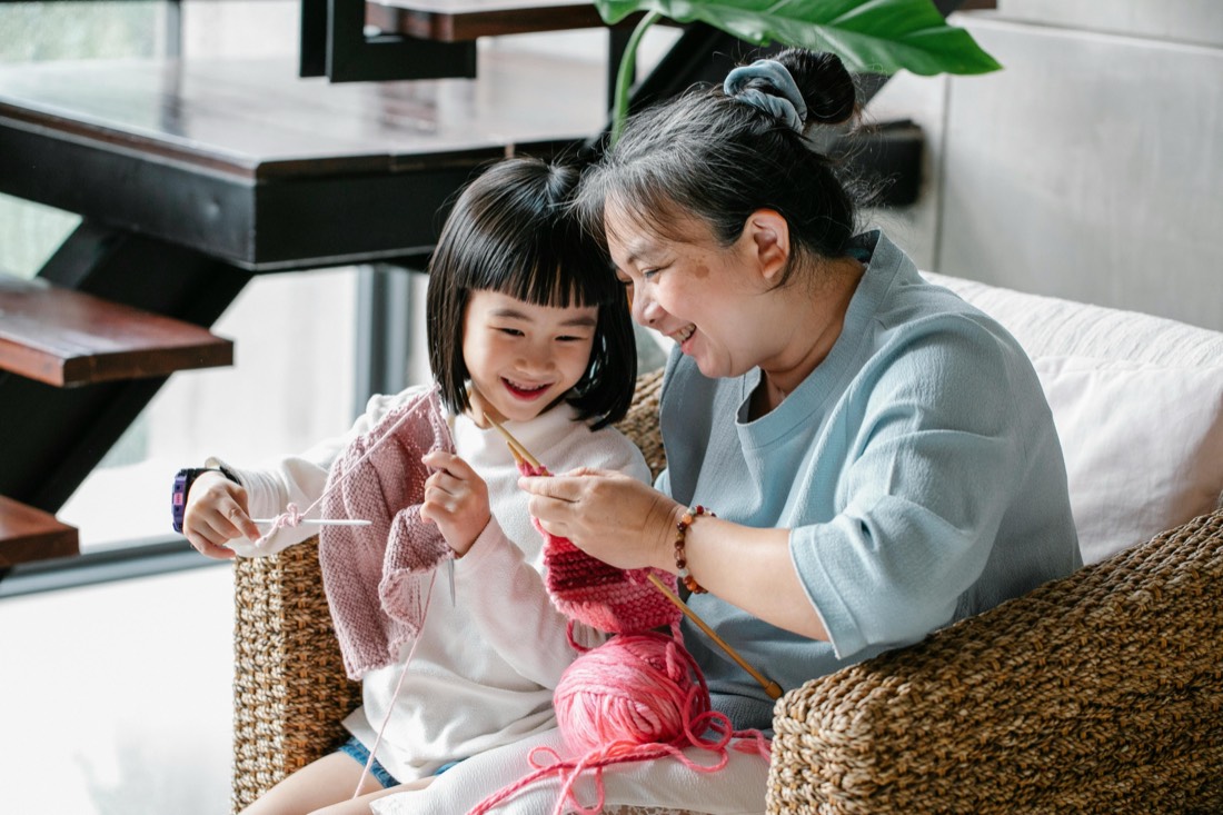 A grandmother and granddaughter knitting together at home