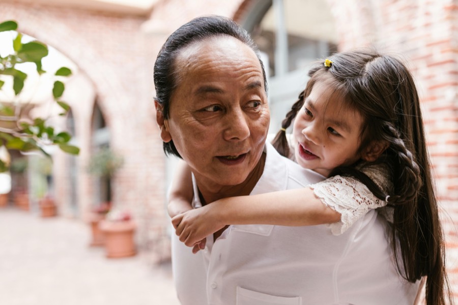 A grandfather carrying his granddaughter on his back