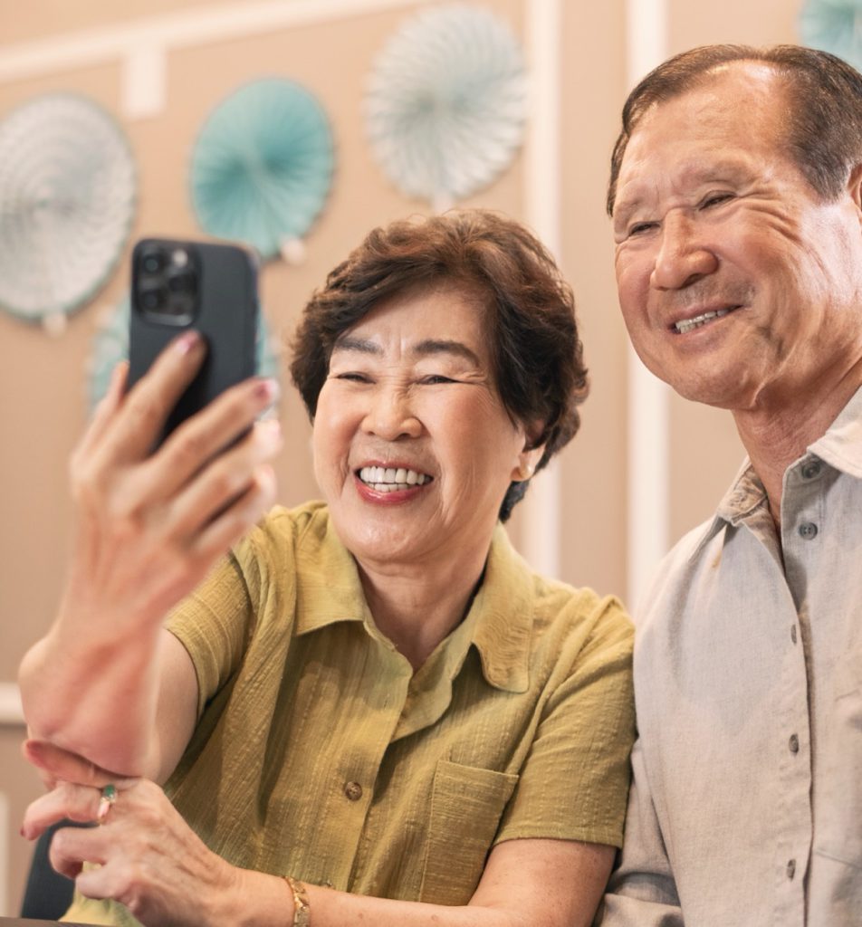 An older couple smiling while looking at a phone together
